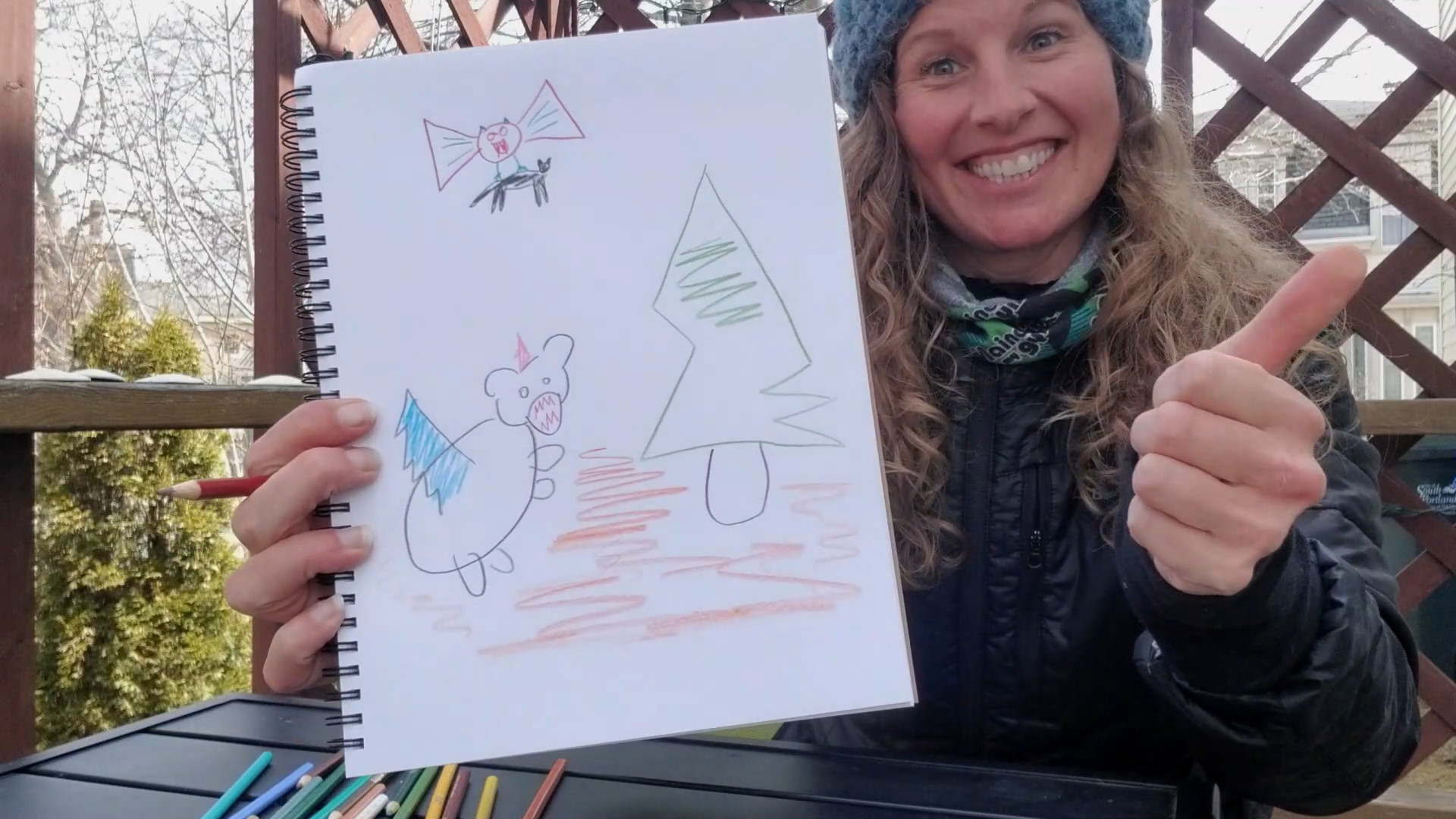 women holding sketchbook with poorly drawn animals on it