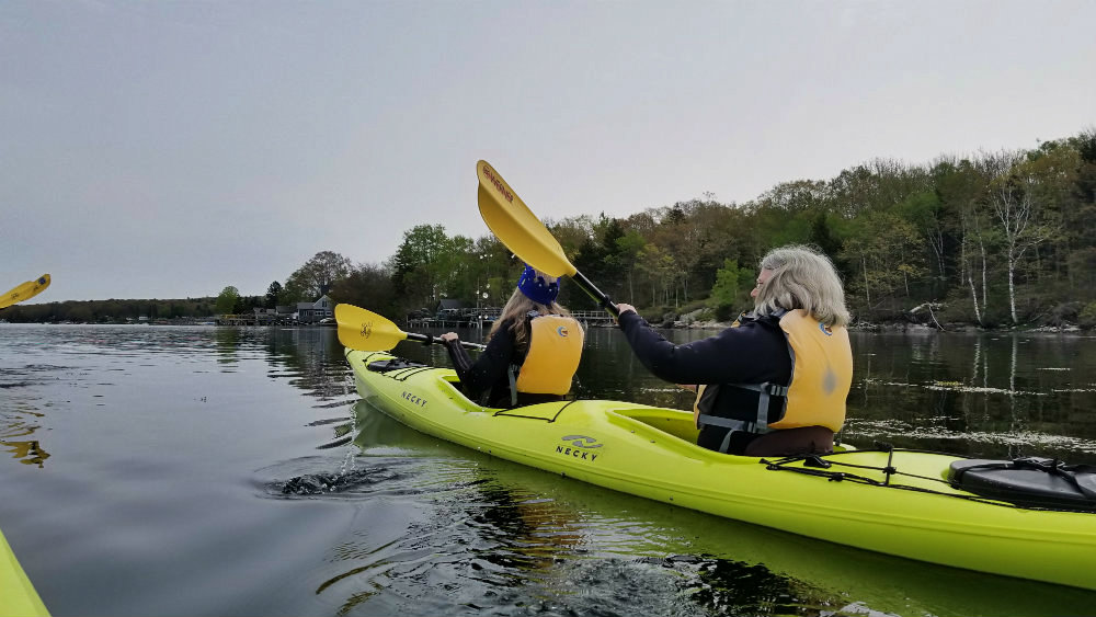 Two women kayaking in a tandem kayak off the coast of Maine
