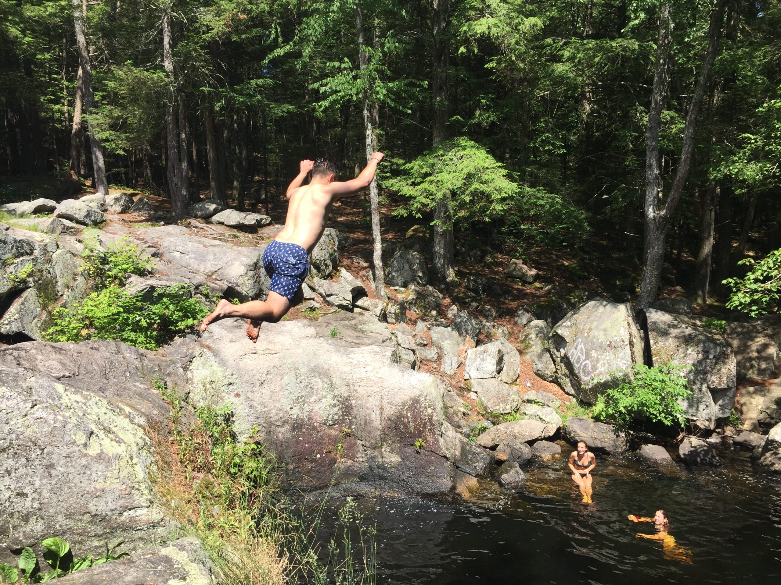 person in shorts jumping into swimming hole